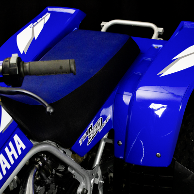 Quadro azul e branco Yamaha YFM 90 com assento e manípulo visíveis