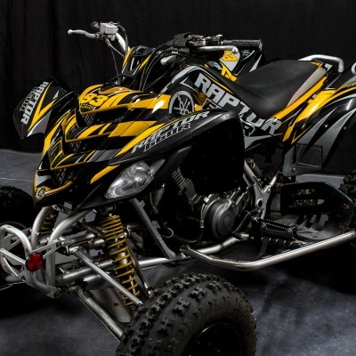Quadriciclo preto e amarelo com texto RAPTOR em fundo escuro