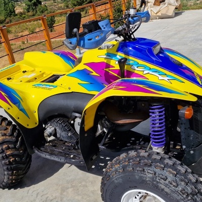 Quad Polaris amarelo com detalhes azul e rosa em piso de cimento ao ar livre