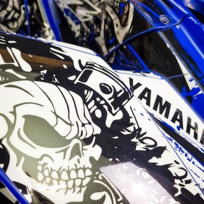 Detalhe de mota ou veículo desportivo azul e branco com caveira e texto YAMAHA
