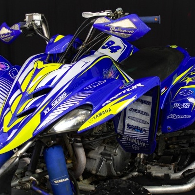 Quadro todo-terreno azul e amarelo com números 94 e marcas Yamaha