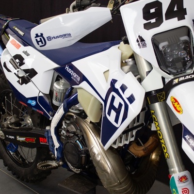 Motocross Husqvarna branca e azul com número 94 e autocolantes diversas marcas