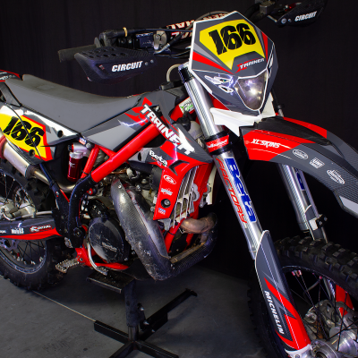 Motocross vermelha e cinza com número 166 em fundo amarelo e vermelho.
