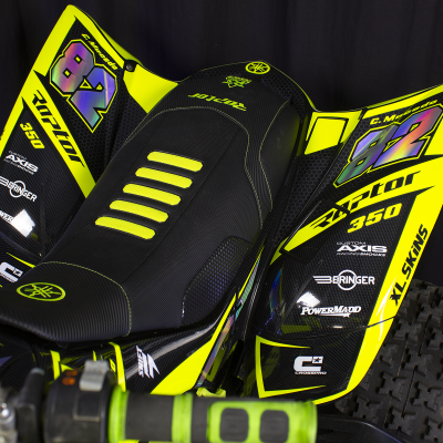 Quadriciclo preto e amarelo com gráficos e textos em fundo preto.