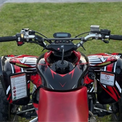 Quadriciclo vermelho e preto com guiador metálico e pneus grandes