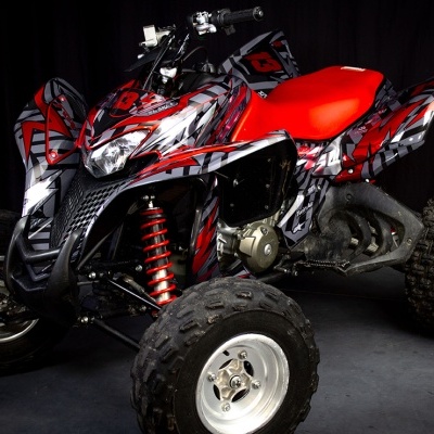 Quad ATV vermelho e preto com padrões abstratos e pneus grandes em fundo escuro