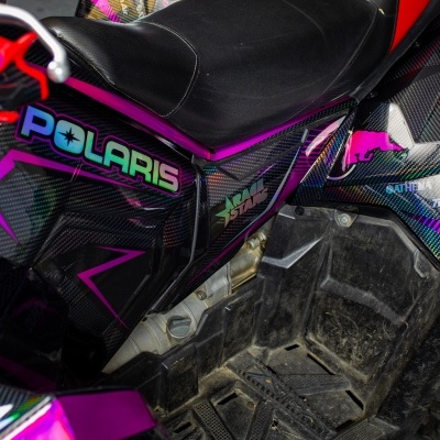 Veículo todo-o-terreno Polaris preto e colorido com pneus robustos e assento de couro preto