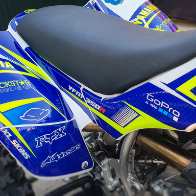 Motocross azul, amarelo e branco com adesivos YAMAHA e GOPRO e assento preto