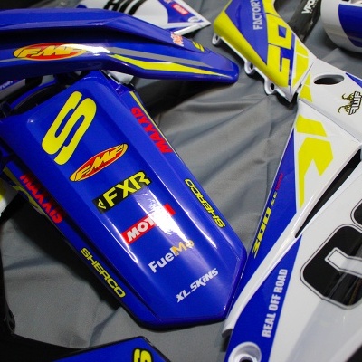 Peças de plástico para motos todo-o-terreno azul, branco e amarelo com números e várias insígnias.