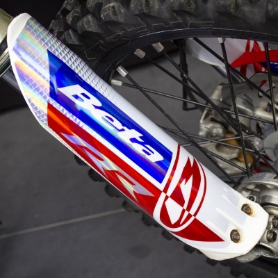 Proteção da suspensão dianteira branca com logotipo Beta em azul numa mota