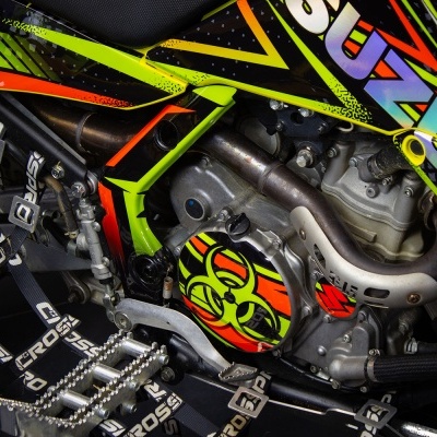 Close-up de motor de mota com carenagem colorida e símbolo de alerta biológico