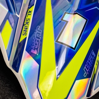 Peça plástica azul, amarela e branca com número 1 e textos JUST1 e XL SKINS