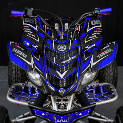 Quad Yamaha azul e preto com vários adesivos e guiador com empunhaduras azuis