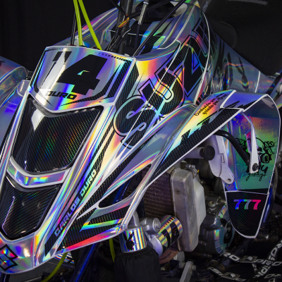 Veículo todo-o-terreno com carenagem holográfica e detalhes pretos com números e texto coloridos.