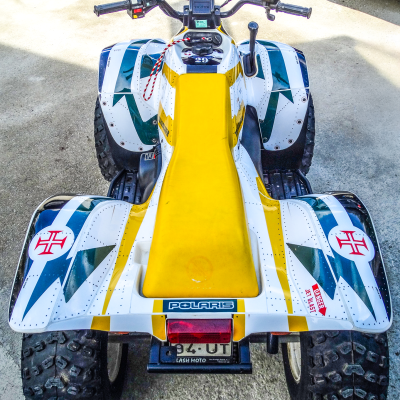 Quad Polaris amarelo e branco com riscas verdes e amarelas, pneus grossos e texto POLARIS