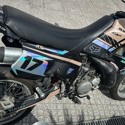 Motocicleta Yamaha DTR 125 preta e bege com assento em pele preta e número 17 holográfico estacionada no exterior
