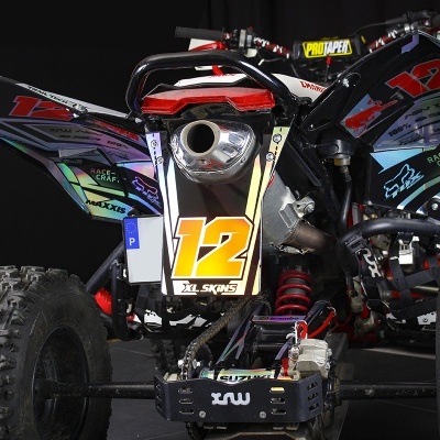 Veículo todo-o-terreno (quad) preto com número 12 e autocolantes coloridos visto de trás