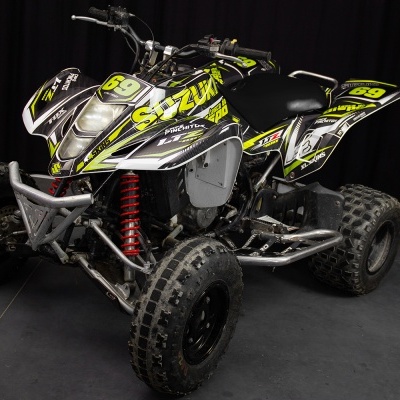 Quadriciclo preto com detalhes amarelos e brancos e texto Suzuki e 69