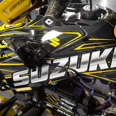 Veículo Suzuki preto com detalhes amarelos e cinzentos e vários logótipos