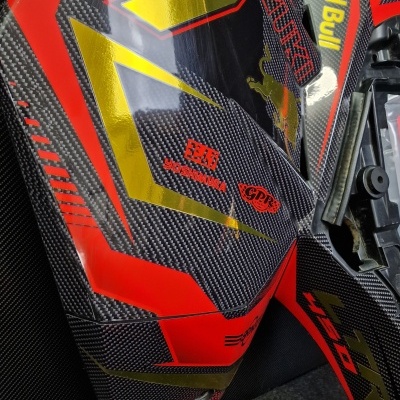 Peças de carenagem de moto em fibra de carbono com gráficos vermelhos, dourados e logótipos