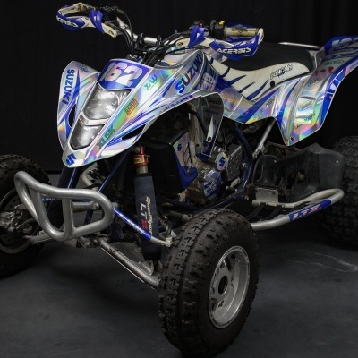 Quadriciclo Suzuki azul e branco com design prateado, pneus grossos e número 53 visível