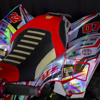 Mota de competição com cores prateadas, vermelhas e pretas e vários autocolantes