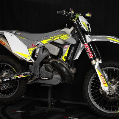 Motocross Sherco cinza e amarelo com pneus off-road e texto em adesivos.