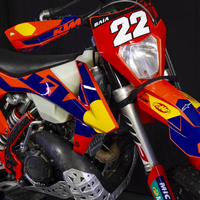 Motocross KTM vermelho, azul e amarelo com número 22 e autocolantes diversos