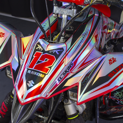 Triciclo Suzuki vermelho, preto e prateado com o número 12 e textos XL-SKINS e SUZUKI XL SK