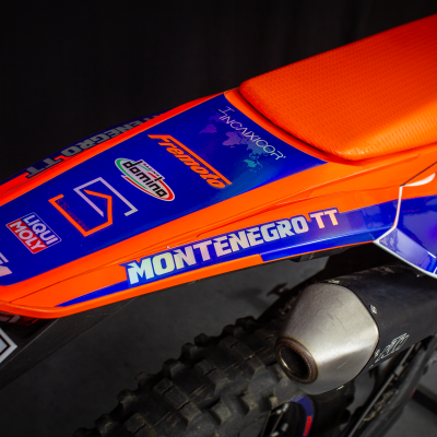 Assento laranja de moto com adesivos azuis e brancos e número 05