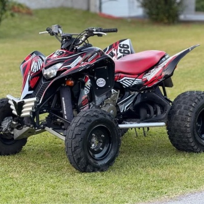 Quadriciclo desportivo preto e vermelho com pneus grandes estacionado em relvado