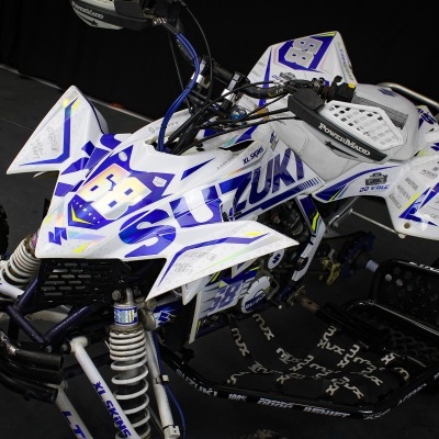 Quadro ATV Suzuki branco com detalhes azuis e roxos em estúdio