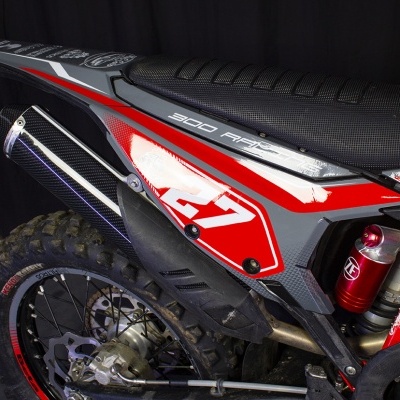 Detalhe traseiro de moto de motocross com escape em fibra de carbono e detalhes em vermelho e cinza