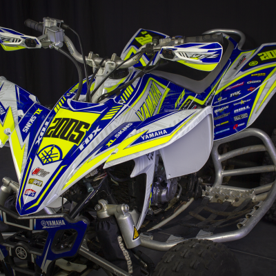 Quad de competição azul, branco e amarelo com adesivos Yamaha e 2005