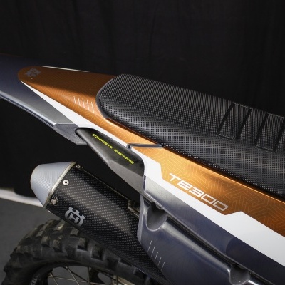 Moto off-road com assento preto e painel lateral castanho e branco com texto TE 300