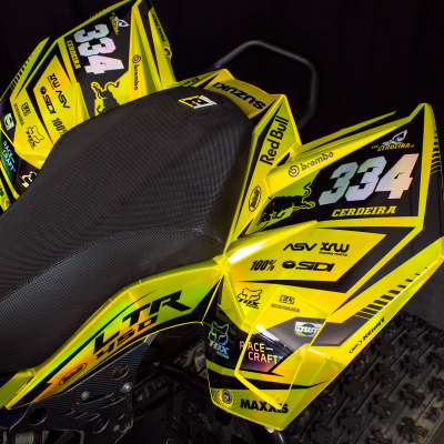 Quadriciclo amarelo e preto com assento preto e adesivos com números e marcas