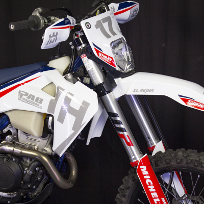 Moto de motocross branca, azul e vermelha com números 14 e 17