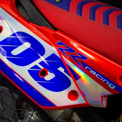 Parte traseira de mota de motocross vermelha e azul com autocolante 06 e ZZ Racing