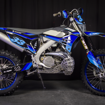 Motocross azul, preto e branco com número 33 em fundo escuro