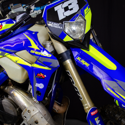 Motocross azul com detalhes amarelos, número 13 e textos SHERCO e FABIO FERREIRA