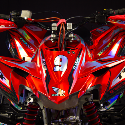 Quad Honda vermelho com autocolantes refletivos e proteções vermelhas nas mãos