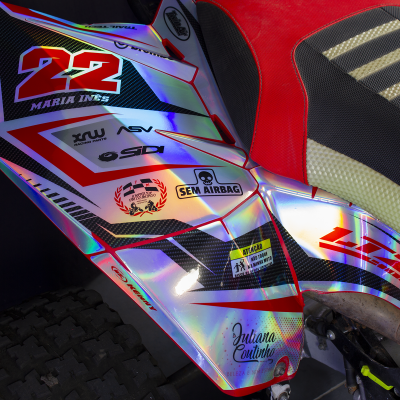 Parte lateral de mota com autocolantes coloridos e assento vermelho e preto texturizado