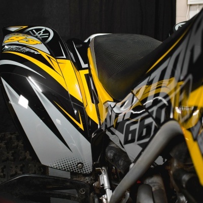 Motociclo de quatro rodas preto, amarelo e branco com detalhes gráficos e número 660