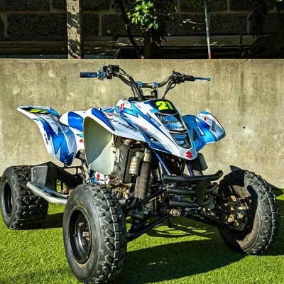 Quadriciclo desportivo branco e azul com número 21 estacionado em relva artificial