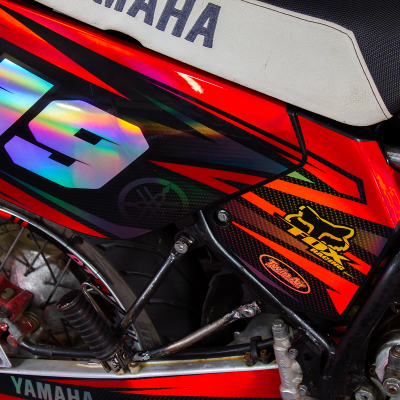 Parte lateral da motocicleta Yamaha com número 19 holográfico e detalhes vermelhos e pretos