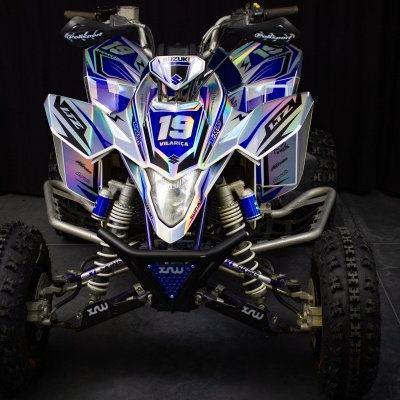 Quadriciclo branco, azul e preto com número 19 em fundo escuro