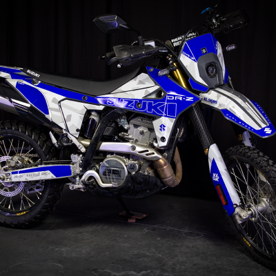 Motociclo Suzuki DR-Z azul e branco em fundo escuro