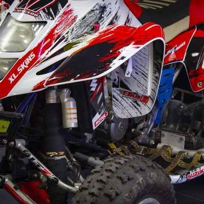 Quad Suzuki branco, vermelho e preto com suspensão e pneus no interior