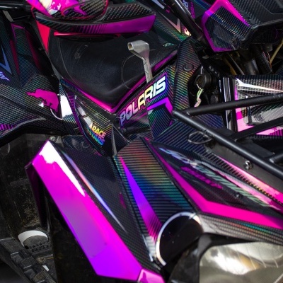 Veículo todo-o-terreno Polaris preto e rosa com número 18 e farol frontal