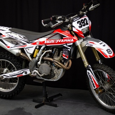 Motocross Husqvarna branca, vermelha e preta com número 392 em suporte